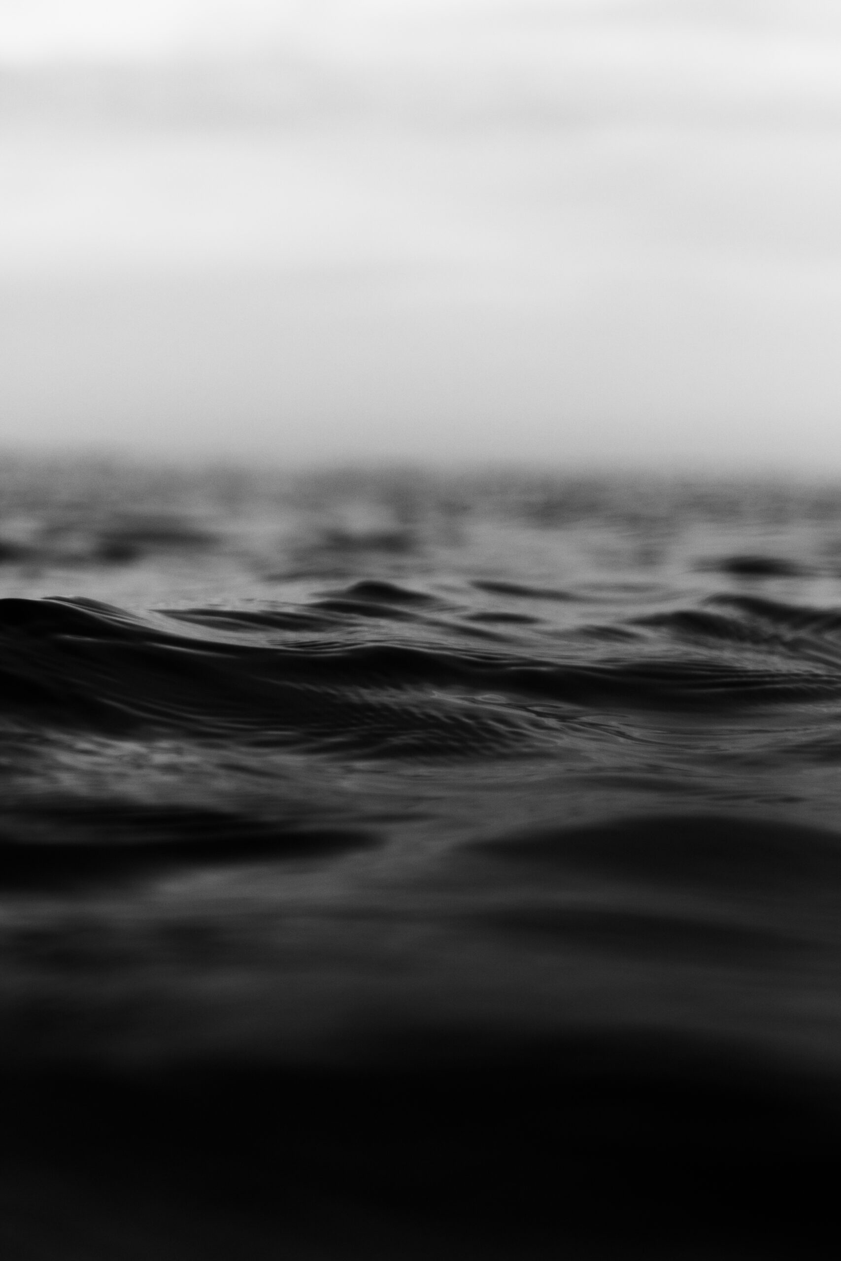 A grayscale vertical shot of tiny rough sea waves